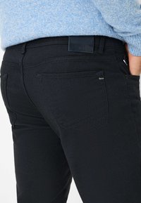 Zwarte spijkerbroeken van denim met een gestructureerde afwerking, voorzien van een subtiele logo op de achterzak en een klassieke snit met achterzakken.