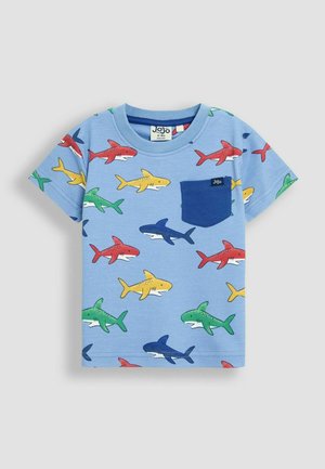 Zils kokvilnas T-krekls ar haizivju motīvu sarkanos, dzeltenos, zaļos un zilos toņos. Uz kreisā krūts ir neliela zila kabata.