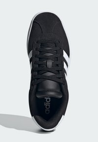 Baskets en suede noir avec des rayures en cuir blanc, bout rond, lacets noirs et languette rembourrée. Présente une semelle texturée et le logo "adidas".