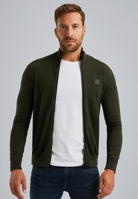 Dunkelgrüne Zip-Jacke im taillierten Design, aus weichem Stoff, mit hohem Kragen und einer aufgesetzten Vordertasche.