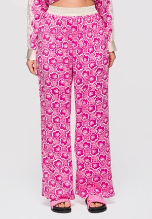 Felroze en witte bloemenprint wijde broek, gecombineerd met een bijpassend topje en zwarte sandalen met roze zachte bandjes.