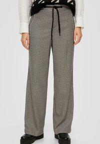 Čierno-biele nohavice so širokými nohavicami a vzorom houndstooth, s elastickým pásom a viazacím detailom na šnúrku. Vyrobené z textúrovanej tkaniny.