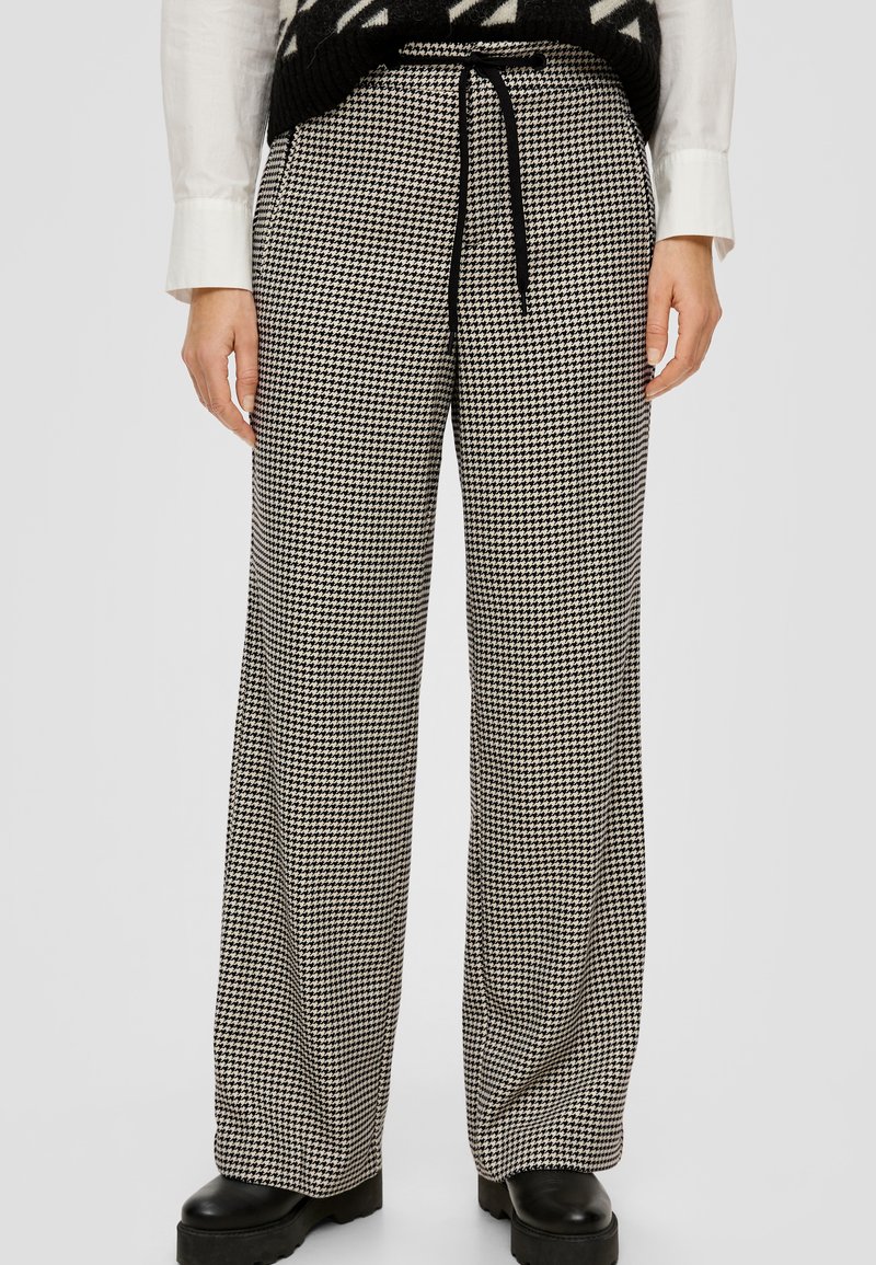 Čierno-biele nohavice so širokými nohavicami a vzorom houndstooth, s elastickým pásom a viazacím detailom na šnúrku. Vyrobené z textúrovanej tkaniny.