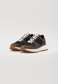 Baskets de sport noires et marron avec des lacets blancs, un motif texturé et une semelle en caoutchouc beige. Présente des accents dorés au niveau du talon.