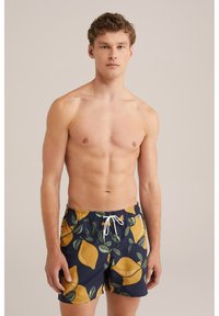 Marineblaues Badehosen mit gelbem Zitronenmuster und grünen Blättern. Verfügt über einen elastischen Taillenbund mit Kordelzug und seitlichen Taschen.