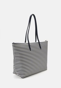 Sac fourre-tout rayé bleu marine et blanc, fabriqué en tissu résistant, avec deux poignées et une fermeture éclair, de forme rectangulaire structurée.