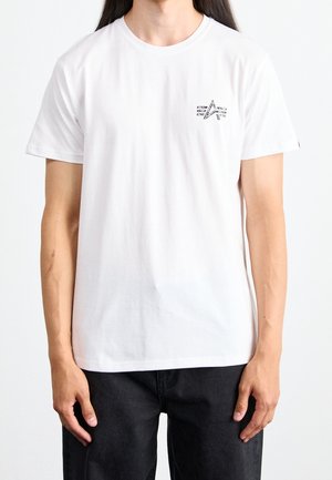 Weißes Baumwoll-T-Shirt mit Rundhalsausschnitt und kurzen Ärmeln. Auf der linken Brustseite befindet sich ein schwarzes grafisches Stern-Design.