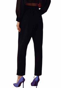 Pantalons noirs fuselés avec une taille élastique, associés à des talons aiguilles violets. Les pantalons ont une texture lisse et un design simple.