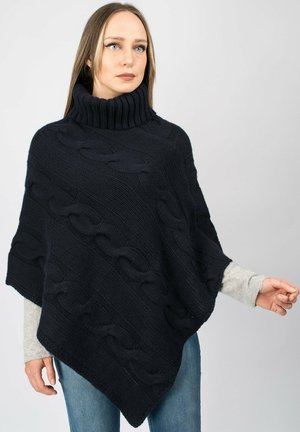 Mørkeblå strikket poncho med høj ribbenkrave, der har kabelstrik mønstre og en skrå kant. Blød tekstur, afslappet pasform.