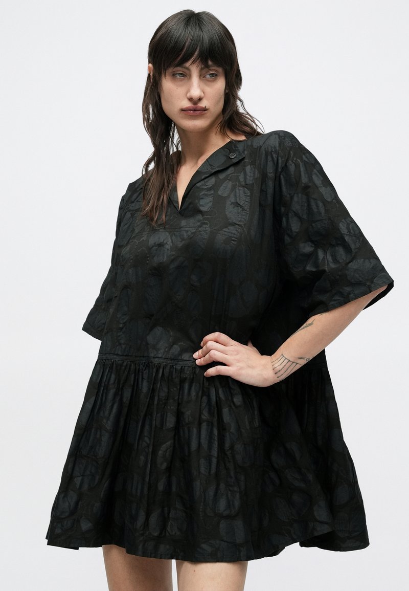 Robe noire à manches courtes avec une coupe ample, dotée d'un col, d'une jupe froncée et d'un motif texturé sur tout le tissu.