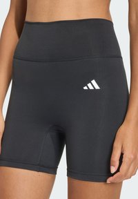 Pantaloncini sportivi neri con una fascia alta in vita, caratterizzati da una texture liscia e dal logo Adidas bianco a contrasto sul lato inferiore sinistro.