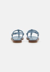 Sandale din piele albastră cu talpă plată, cu un design de tip t-strap și cataramă ajustabilă la gleznă. Tălpiu texturat și accente din lemn.