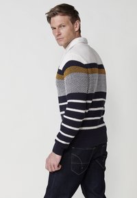 Suéter de punto con cuello doblado que presenta rayas horizontales en azul marino, blanco y mostaza. Puños y dobladillo acanalados; tejido texturizado.