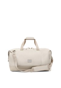 Beige Duffel Bag mit zwei Griffen, verstellbarem Schultergurt und Fronttasche mit einem Markenlabel auf weißem Hintergrund.