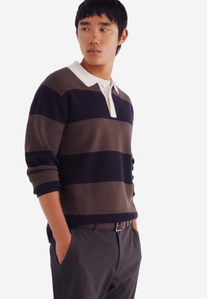 Gestreepte gebreide sweater in marineblauw, bruin en crème, met een kraag en een drieknoopsluiting. Gepaard met grijze broek.
