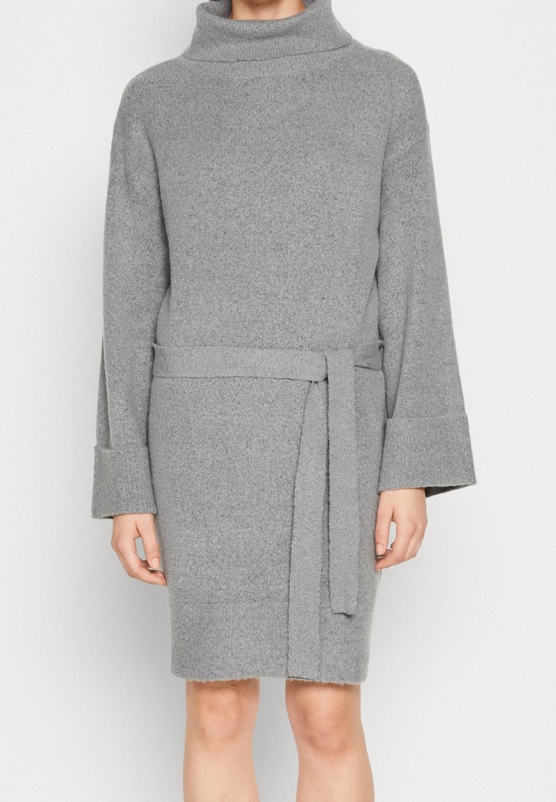 Vestido gris de punto con cuello alto, mangas largas y un cinturón a juego. Presenta un acabado texturizado y una longitud hasta medio muslo.