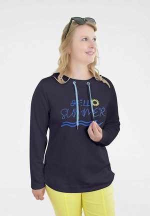 Marineblauer Kapuzenpullover mit "Hello Summer"-Grafik in Blau und Gelb, ausgestattet mit einer Kordelzugkapuze und langen Ärmeln, kombiniert mit gelben Hosen.