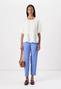 Hvit, stripete peplum-top med puffy ermer, kombinert med lyseblå skreddersydde bukser. Brun veske og loafers med leopardmønster.