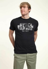 Camiseta negra con texto "STAR WARS" y gráficos de personajes en blanco. Mangas cortas, cuello redondo, tejido de mezcla de algodón.