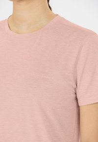 Ljusrosa kortärmad t-shirt gjord av mjukt tyg. Har en subtil "ENDURANCE"-logotyp i vitt på bröstet, med rund halsringning.