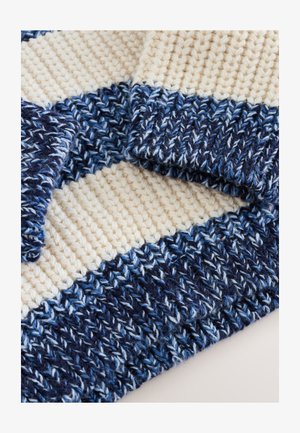 Strickstoff mit abwechselnden Streifen in Creme und verschiedenen Blau- und Blautönen. Strukturmuster mit einer dicken, gerippten Kante. Weich und gemütlich.