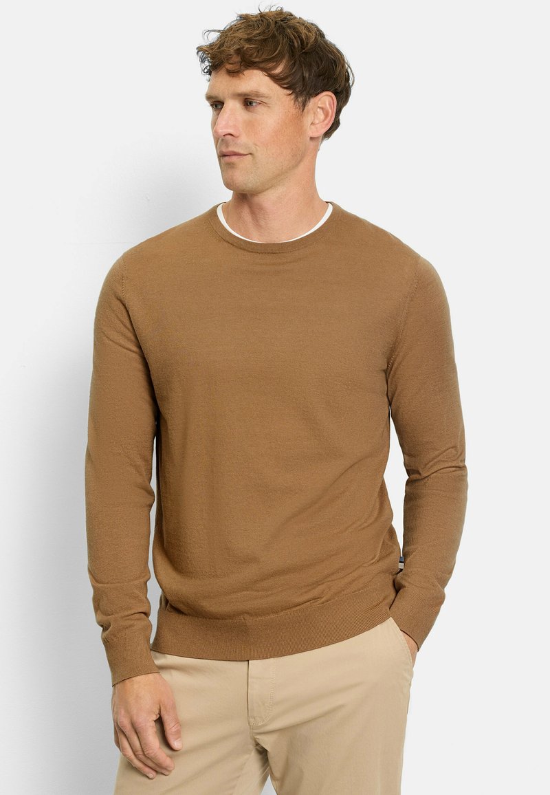 Brauner langärmliger Pullover mit Rundhalsausschnitt, gerippten Bündchen und Saum, aus einem weichen Strickstoff, kombiniert mit beigen Hosen.