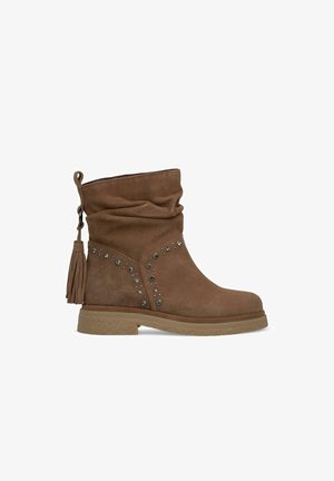 Braune Wildleder-Ankle Boots mit lässigem Design, Quastendetail und dekorativen Nieten an der Seite. Dicke Sohle mit strukturiertem Finish.