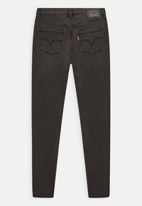 Vaqueros de mezclilla negra con un ajuste ajustado. Presenta dos bolsillos traseros y una etiqueta de marca en la cintura. Textura suave y diseño limpio.