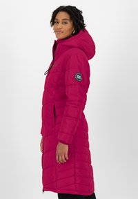 Langer rosa Daunenmantel mit Kapuze, mit gestepptem Material, Saum bis zur Mitte des Oberschenkels und einem Patch an der linken Ärmel. Zwei Seitentaschen.