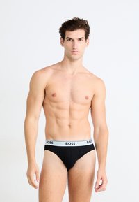 Slip noir avec une ceinture élastique blanche comportant le logo "BOSS". Tissu doux et extensible, conçu pour le confort et l'ajustement.