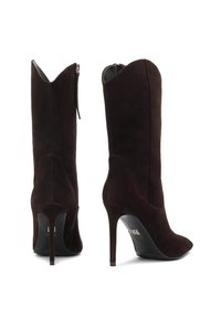 Botas altas de ante marrón con tacones altos y punteras afiladas, cremalleras laterales y un caña alta con un diseño superior en forma de onda distintivo.