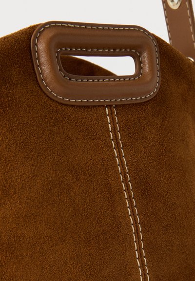 Καφέ τσάντα από σουέτ με ορθογώνιο δερμάτινο χερούλι, διακοσμητική ραφή και εμφανές ραμμένο μέρος στο κέντρο.
