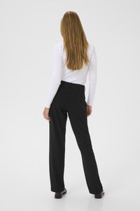 Black trousers with a tailored design, featuring a slight sheen, straight legs, and back pockets. Paired with a white long-sleeve top.