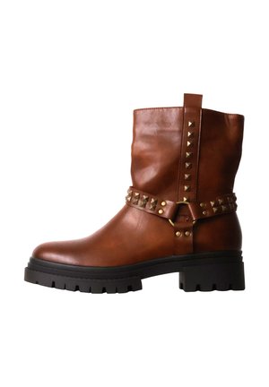Botte en cuir marron de hauteur moyenne avec semelle noire épaisse, sangle décorative et bande verticale avec clous métalliques carrés sur fond blanc.