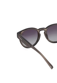 Sluneční brýle ve stylu kočičích očí s gradientním šedým sklem, tmavě želvovinovým rámem a světlými hnědými nohami. Na straně se nachází logo Timberland.