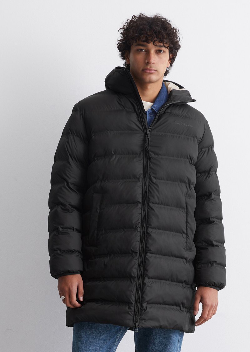 Schwarze Daunenjacke mit Reißverschluss und Kapuze, mit horizontalen Steppnähten und Seitentaschen. Getragen über einem blauen Hemd.