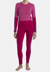 Snygg träningsoberdel och leggings i rosa med blåa accenter, långa ärmar och mjuk textur. Toppen har en rund halsringning och kontrasterande ärmdesign.