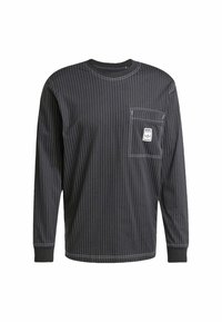 Black long-sleeve shirt with white vertical stripes, round neckline, front pocket, and label accent on pocket. Heavyweight cotton fabric.