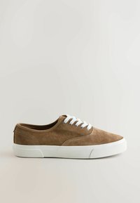 Baskets basses en daim marron avec semelle en caoutchouc blanche et lacets blancs, vues de profil sur un fond clair.