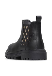 Bottines Chelsea en cuir noir avec panneau en tissu texturé arborant des motifs de cœurs dorés, des ganses élastiques sur les côtés et une semelle épaisse et durable.
