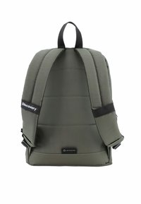 Mochila verde oliva con textura acolchada, correas ajustables, asa superior y etiqueta con logo. El material es tela de PET reciclado, diseñada para ser duradera.
