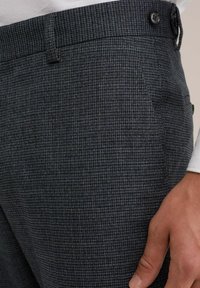 Grå rutig byxa i strukturväv. Har en platt front, knäppning med knapp och sidofickor. Tätt snitt med minimal detaljering.