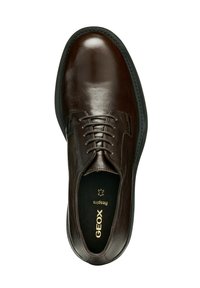 Zapato de cuero marrón con un acabado suave, punta redondeada, diseño de cordones y suela de goma negra. Cuenta con un logotipo dorado en el interior.