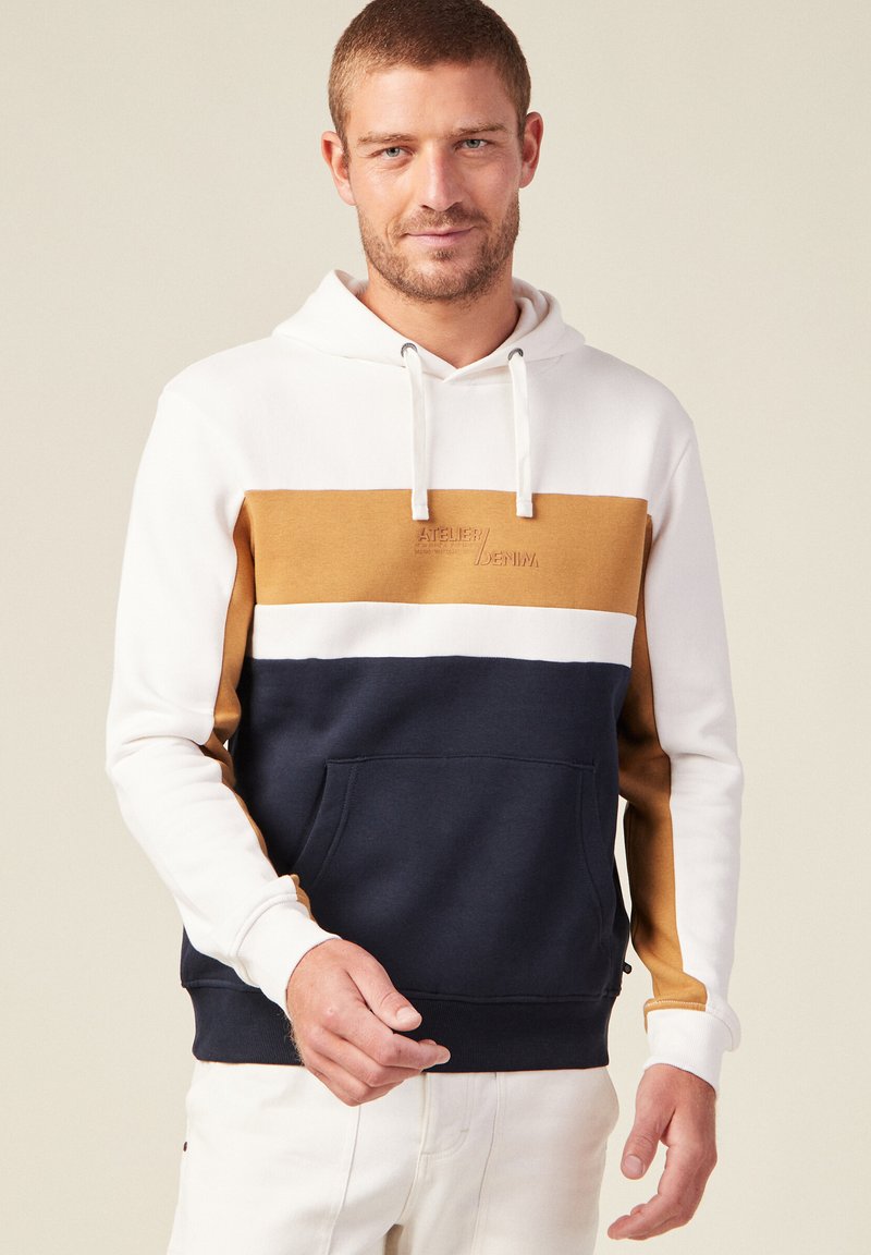 Felpa con cappuccio a blocchi di colore in crema, senape, bianco e blu navy. Presenta una tasca a marsupio e cappuccio con coulisse.
