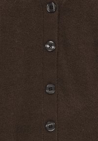 Gros plan d’un tissu tricoté marron foncé avec quatre boutons ronds noirs espacés uniformément en rangée verticale.