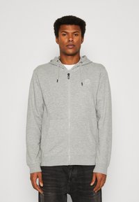 Gray zip-up hoodie made of soft fabric, featuring a drawstring hood, front pockets, and a subtle logo accent on the chest.