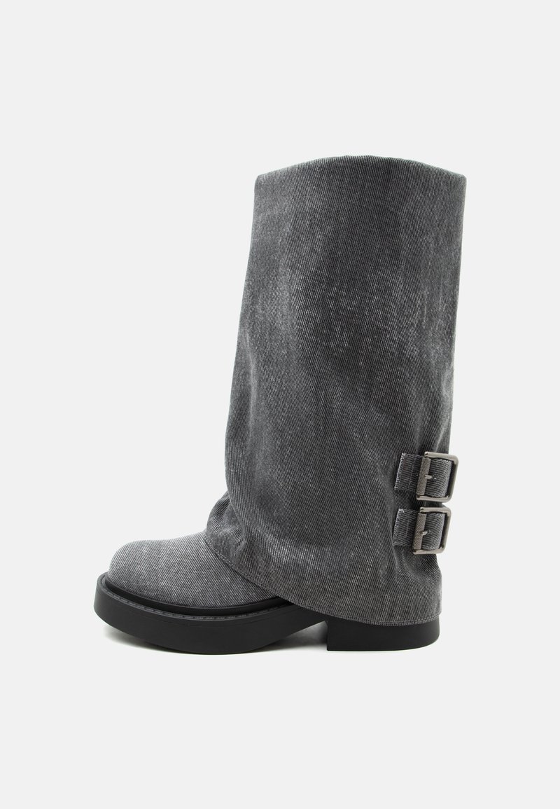 Botte grise molle mi-mollet avec semelle noire et deux boucles latérales ajustables, vue de profil sur fond blanc.