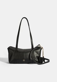 Zwarte leren handtas met twee lange hengsels, gebogen vorm, gouden hardware-accent, en een afneembare strap met een charm. Soepele textuur.