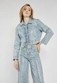 Krótkie dżinsowe kurtki i spodnie z wysokim stanem w jasnoniebieskim kolorze z błyszczącą, brokatową fakturą; zawiera guziki i klasyczny krój kołnierza.