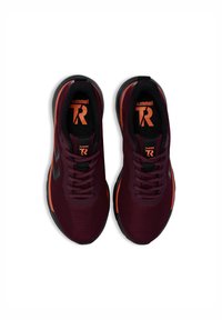 Baskets de sport bordeaux avec une tige en maille texturée, lacets noirs et accents orange. Équipées d'une semelle noire et d'un logo sur la languette.